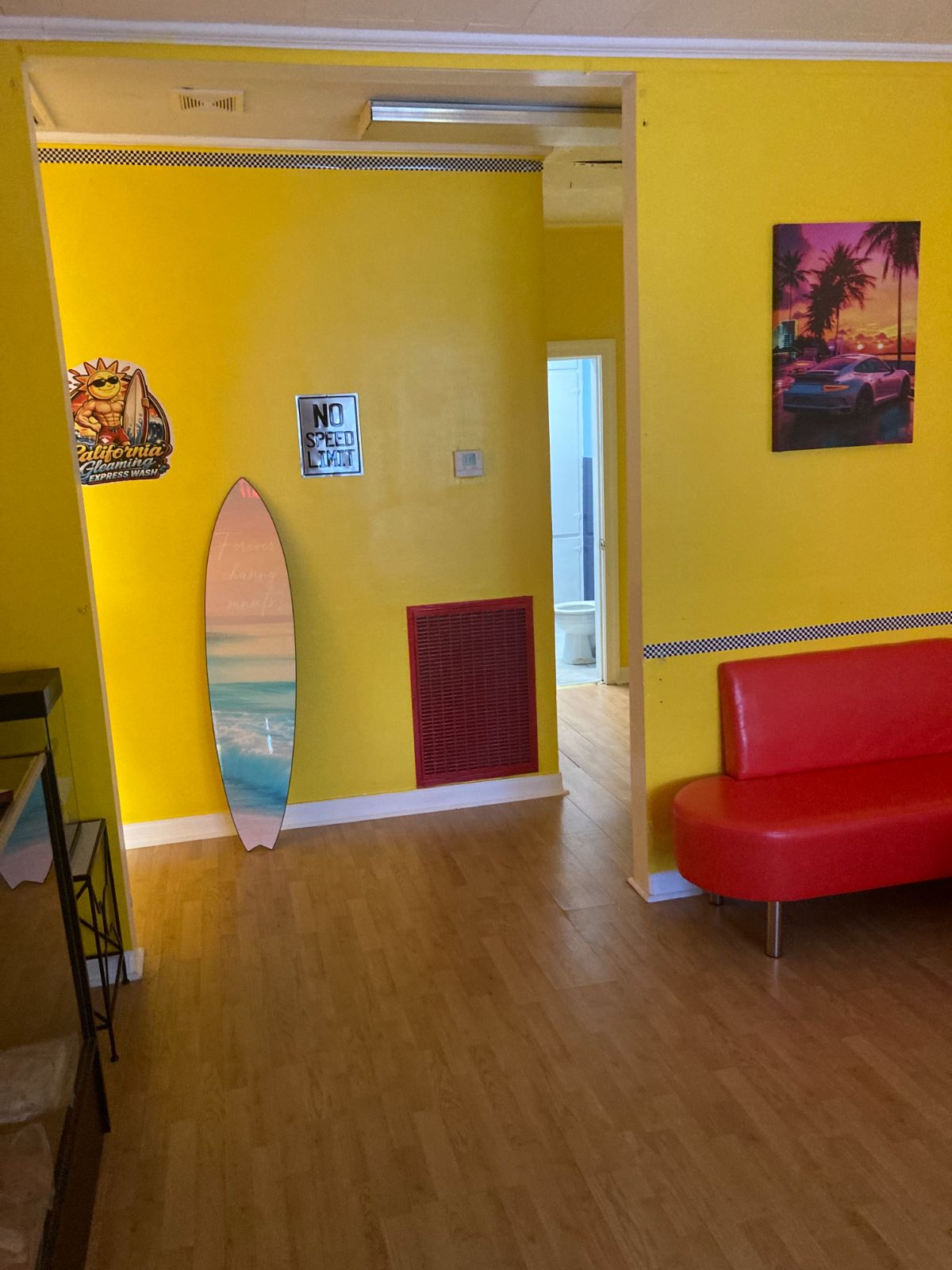 Customer lounge with yellow walls, surfboard mirror and red seating
